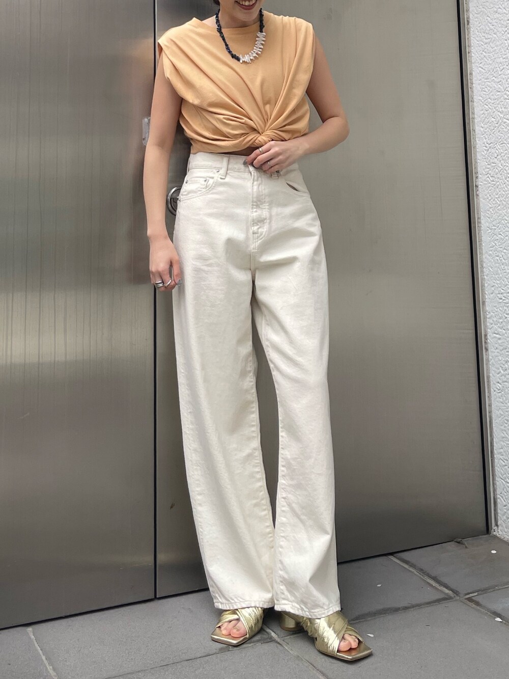 ホワイト系のデニムパンツ、ゴールド系のサンダルを着用したレディースの春コーディネートの7枚目の写真