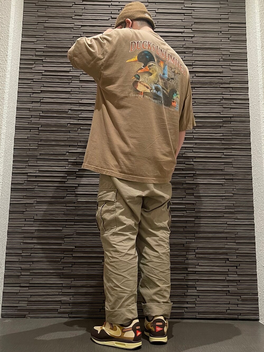 ベージュ系のカーゴパンツ、ブラウン系のTシャツ/カットソー、ブラウン系のスニーカーを着用したメンズの夏コーディネートの2枚目の写真