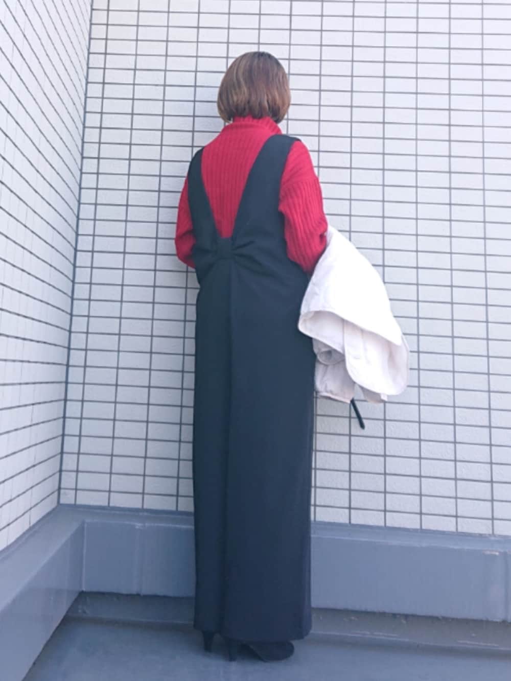 レッド系のニット/セーター、ブラック系のブーツ、ブラック系のサロペット/オーバーオールを着用したレディースの冬コーディネートの2枚目の写真