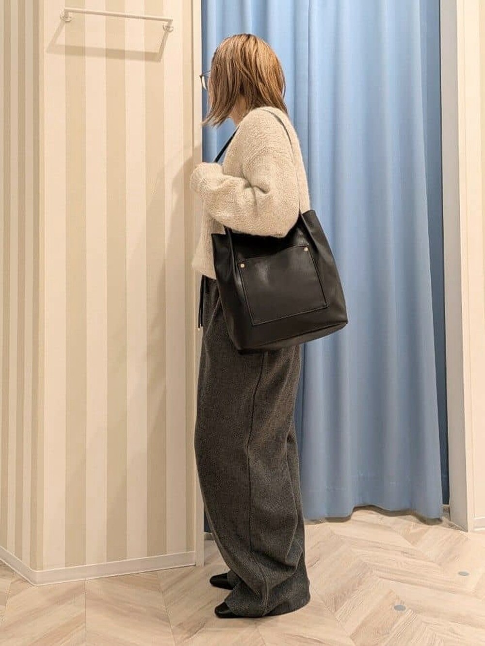 ホワイト系のニット/セーター、ブラック系のその他パンツ、ブラック系のトートバッグを着用したレディースの冬コーディネートの2枚目の写真