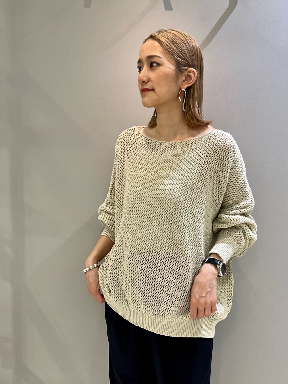 ベージュ系のハンドバッグ、ゴールド系のニット/セーター、ブルー系のその他パンツを着用したレディースの春コーディネートの3枚目の写真