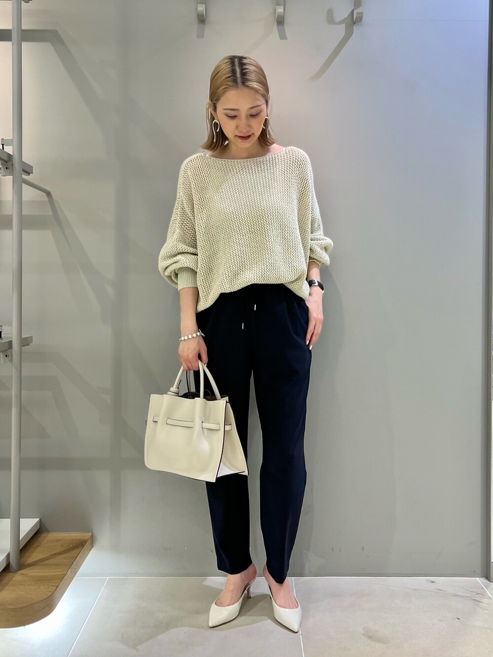 ベージュ系のハンドバッグ、ゴールド系のニット/セーター、ブルー系のその他パンツを着用したレディースの春コーディネートの2枚目の写真