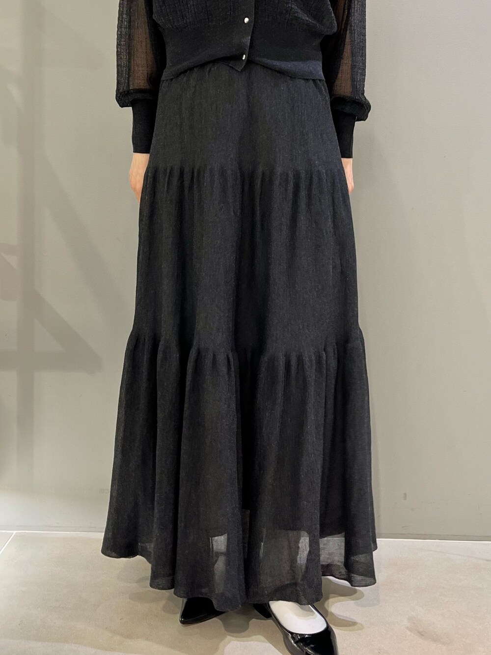 グレー系のカーディガン/ボレロ、ブラック系のショルダーバッグ、グレー系のスカートを着用したレディースの春コーディネートの3枚目の写真