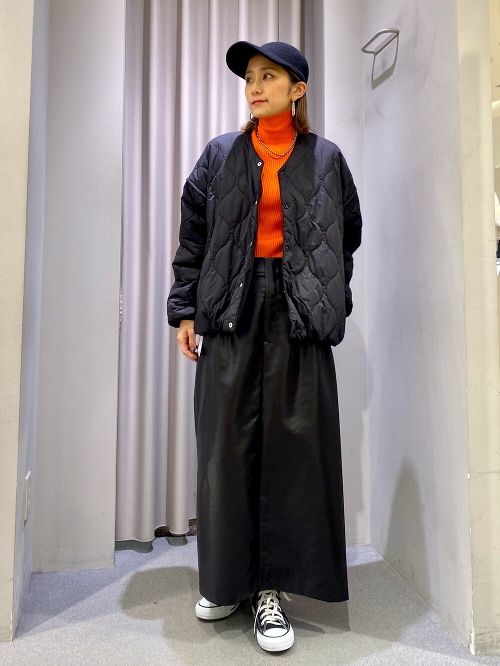 ブラック系のスカート、オレンジ系のニット/セーター、ブラック系のジャケット/アウターを着用したレディースの冬コーディネートの2枚目の写真