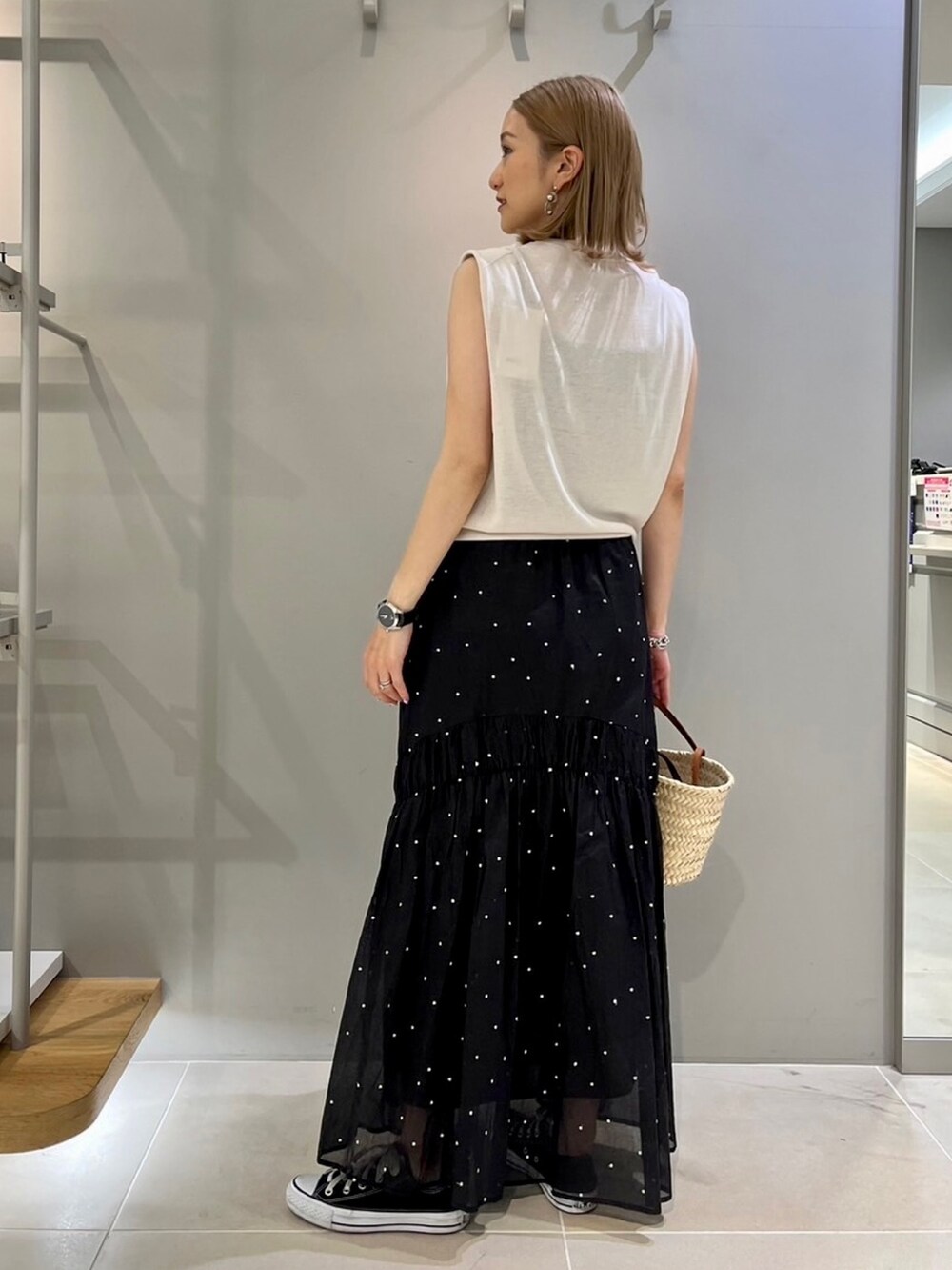 グレー系のニット/セーター、ブラック系のスカート、ブラウン系のショルダーバッグを着用したレディースの夏コーディネートの2枚目の写真