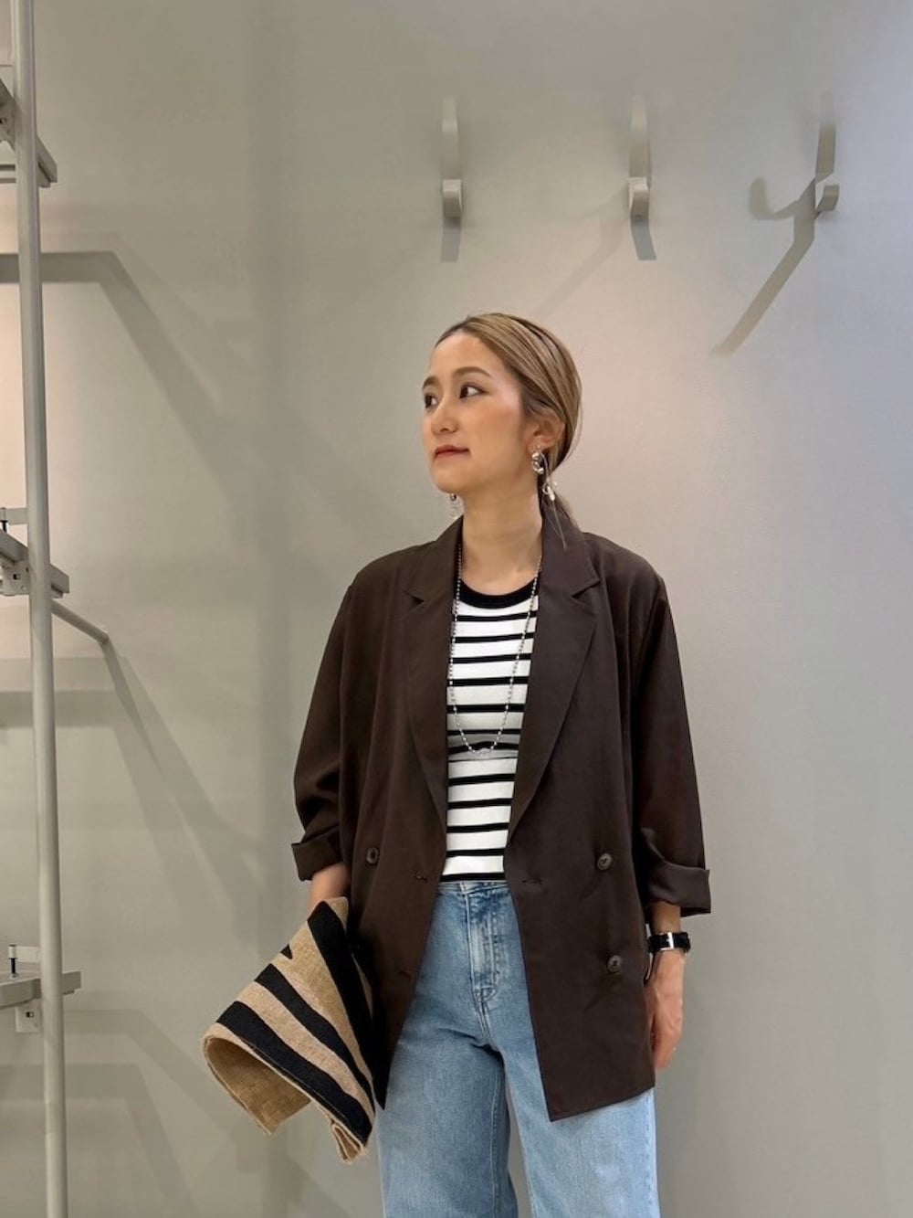 ブラウン系のテーラードジャケット、ブルー系のデニムパンツ、その他のトートバッグを着用したレディースの夏コーディネートの4枚目の写真