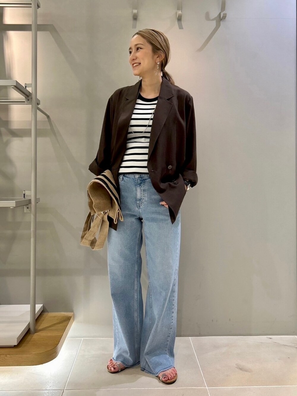 ブラウン系のテーラードジャケット、ブルー系のデニムパンツ、その他のトートバッグを着用したレディースの夏コーディネートの2枚目の写真