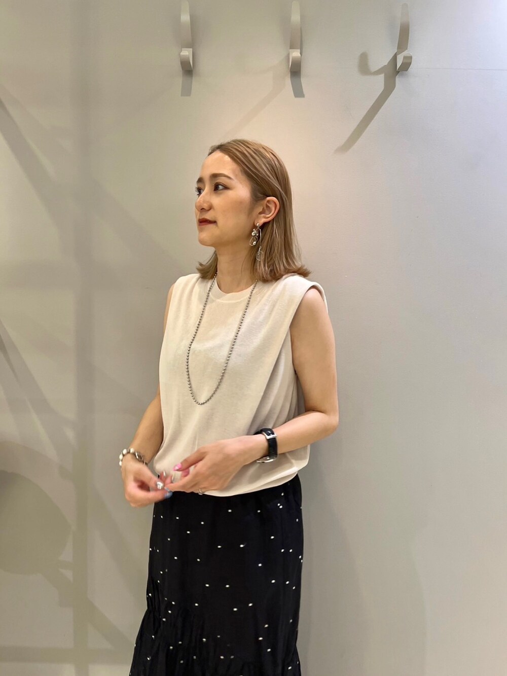 グレー系のニット/セーター、ブラック系のスカート、ブラウン系のショルダーバッグを着用したレディースの夏コーディネートの3枚目の写真