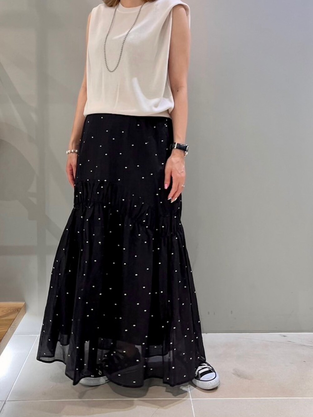 グレー系のニット/セーター、ブラック系のスカート、ブラウン系のショルダーバッグを着用したレディースの夏コーディネートの6枚目の写真