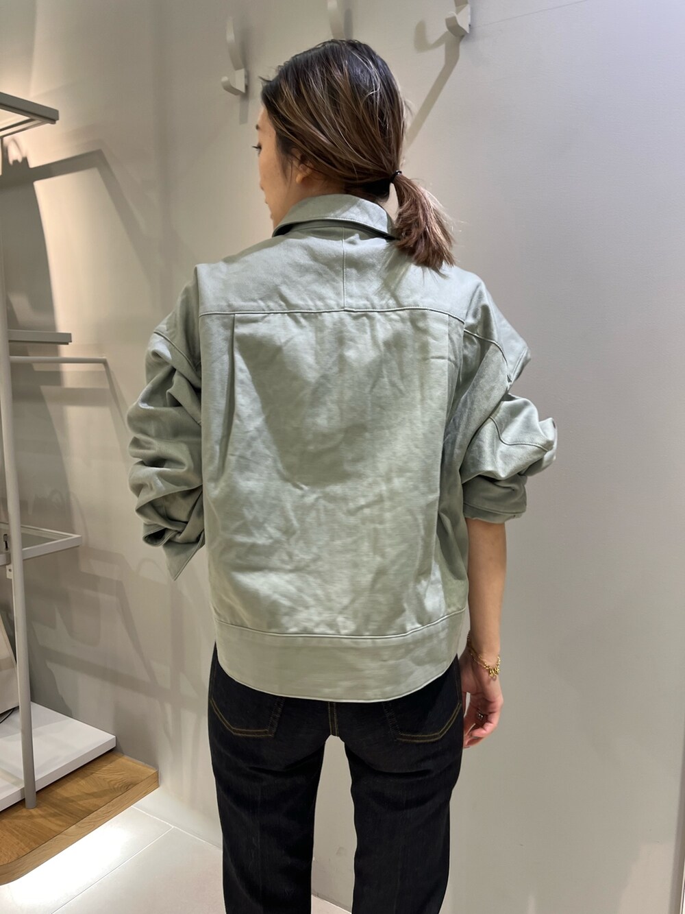 グリーン系のブルゾン、ブラック系のショルダーバッグ、ブルー系のデニムパンツを着用したレディースの冬コーディネートの3枚目の写真