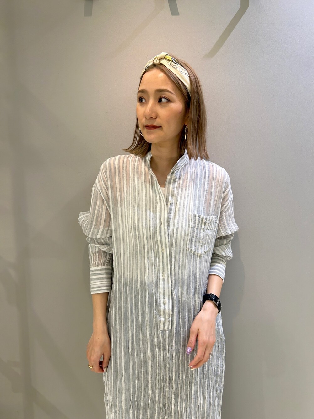 グレー系のワンピース、ブラウン系のショルダーバッグ、ブルー系のデニムパンツを着用したレディースの春コーディネートの4枚目の写真