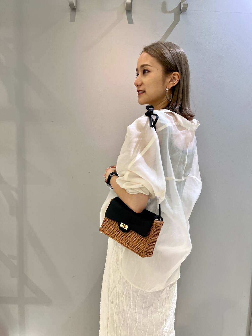 ホワイト系のシャツ/ブラウス、ホワイト系のスカート、ブラック系のショルダーバッグを着用したレディースの春コーディネートの4枚目の写真