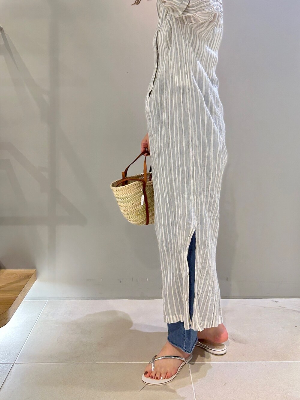 グレー系のワンピース、ブラウン系のショルダーバッグ、ブルー系のデニムパンツを着用したレディースの春コーディネートの3枚目の写真