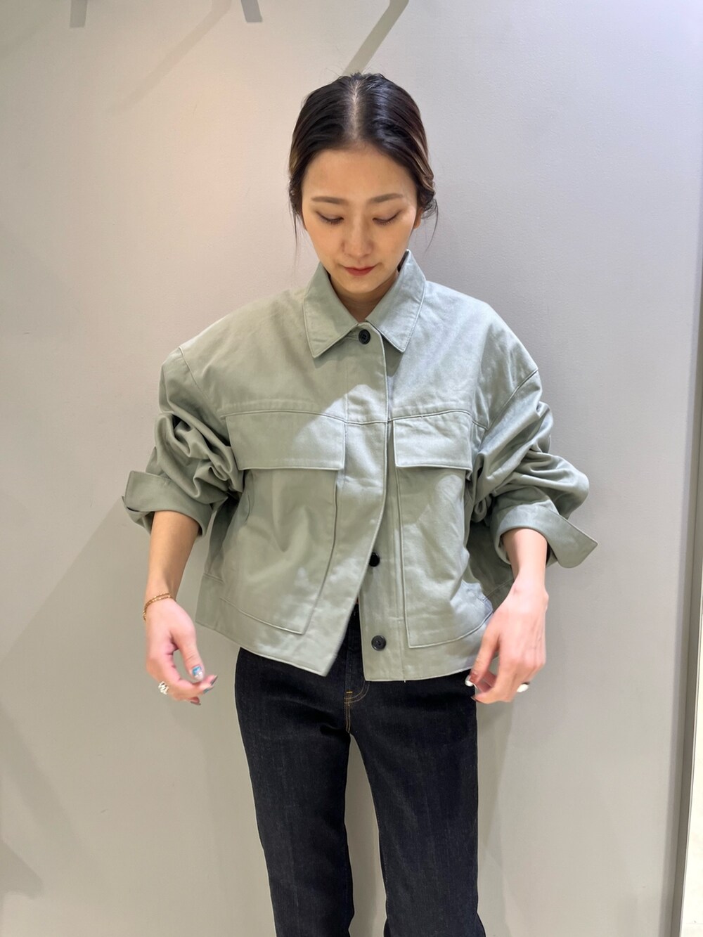 グリーン系のブルゾン、ブラック系のショルダーバッグ、ブルー系のデニムパンツを着用したレディースの冬コーディネートの2枚目の写真