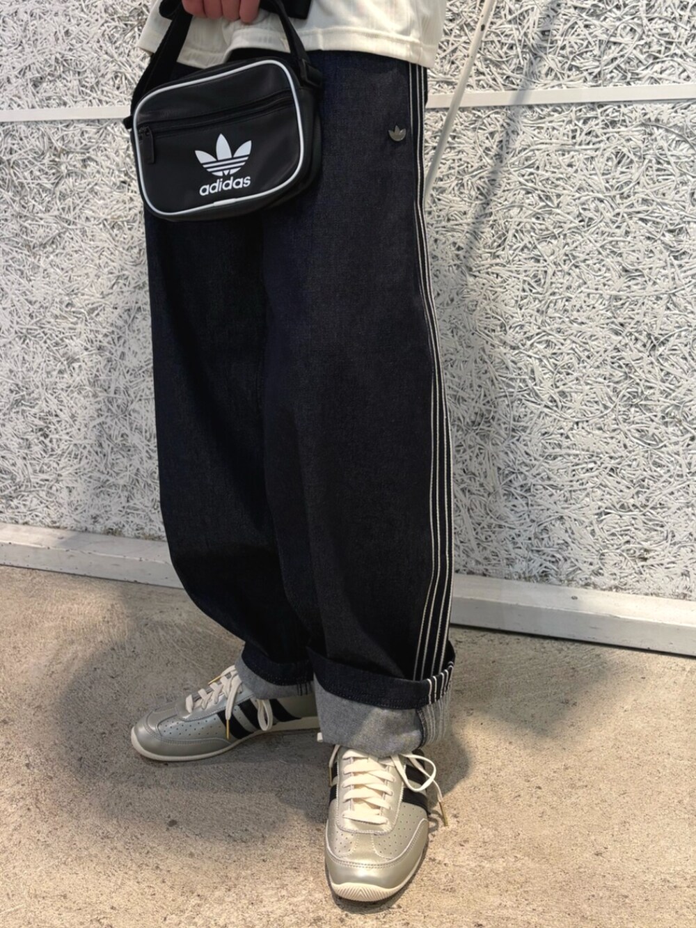 ブラック系のショルダーバッグ、ブルー系のデニムパンツ、ホワイト系のトップスを着用したメンズの夏コーディネートの3枚目の写真