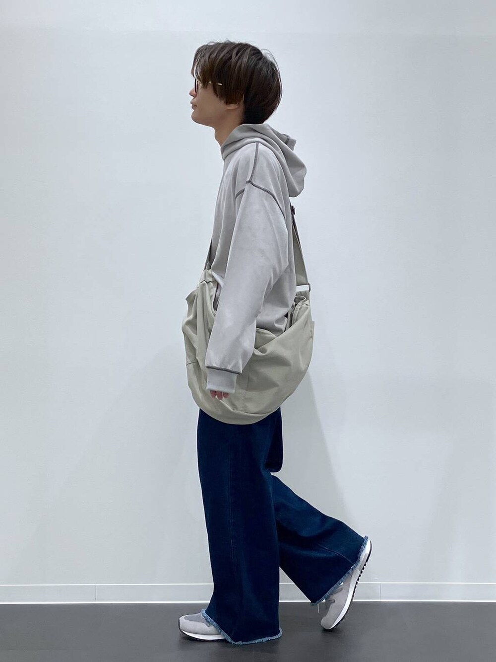 グレー系のショルダーバッグ、ブルー系のデニムパンツ、グレー系のスニーカーを着用したメンズの秋コーディネートの2枚目の写真