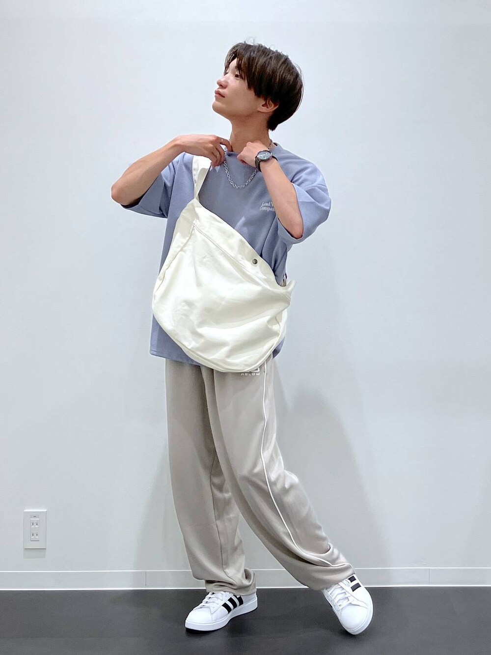 ブルー系のTシャツ/カットソー、ベージュ系のショルダーバッグ、ホワイト系のスニーカーを着用したメンズの夏コーディネートの4枚目の写真