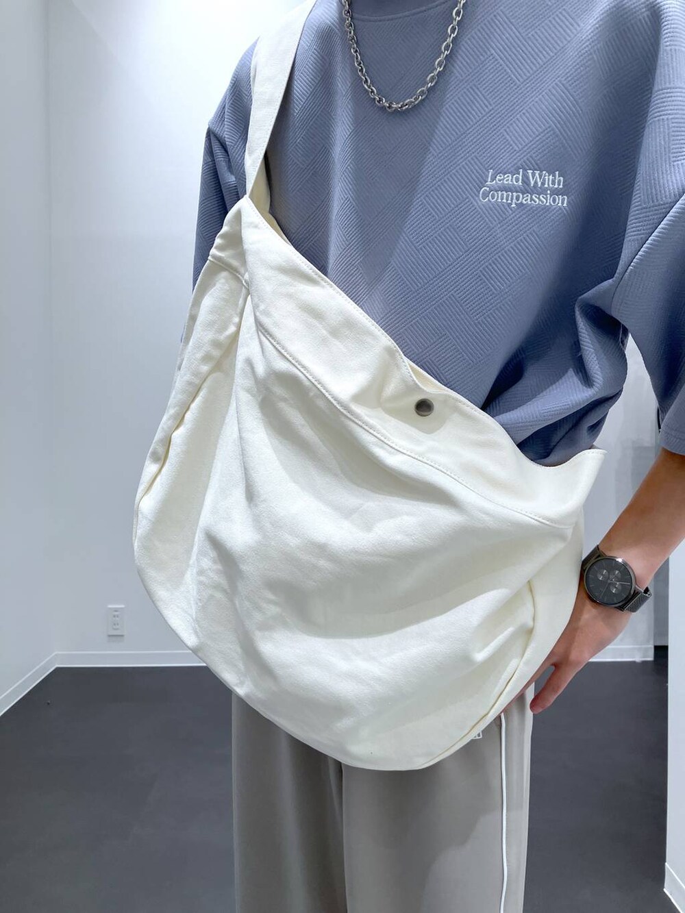 ブルー系のTシャツ/カットソー、ベージュ系のショルダーバッグ、ホワイト系のスニーカーを着用したメンズの夏コーディネートの7枚目の写真