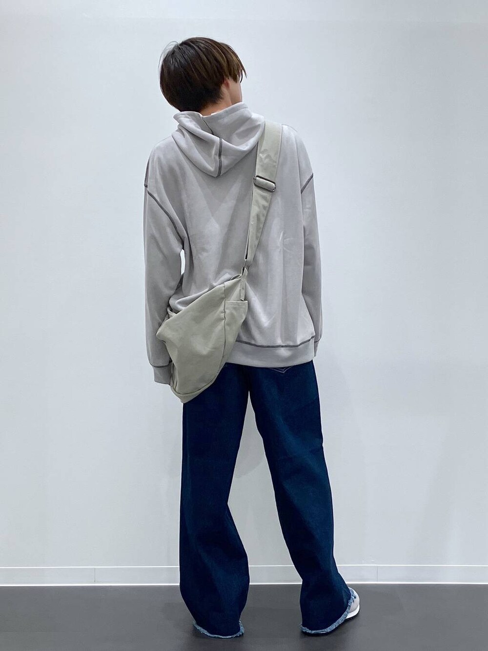 グレー系のショルダーバッグ、ブルー系のデニムパンツ、グレー系のスニーカーを着用したメンズの秋コーディネートの3枚目の写真