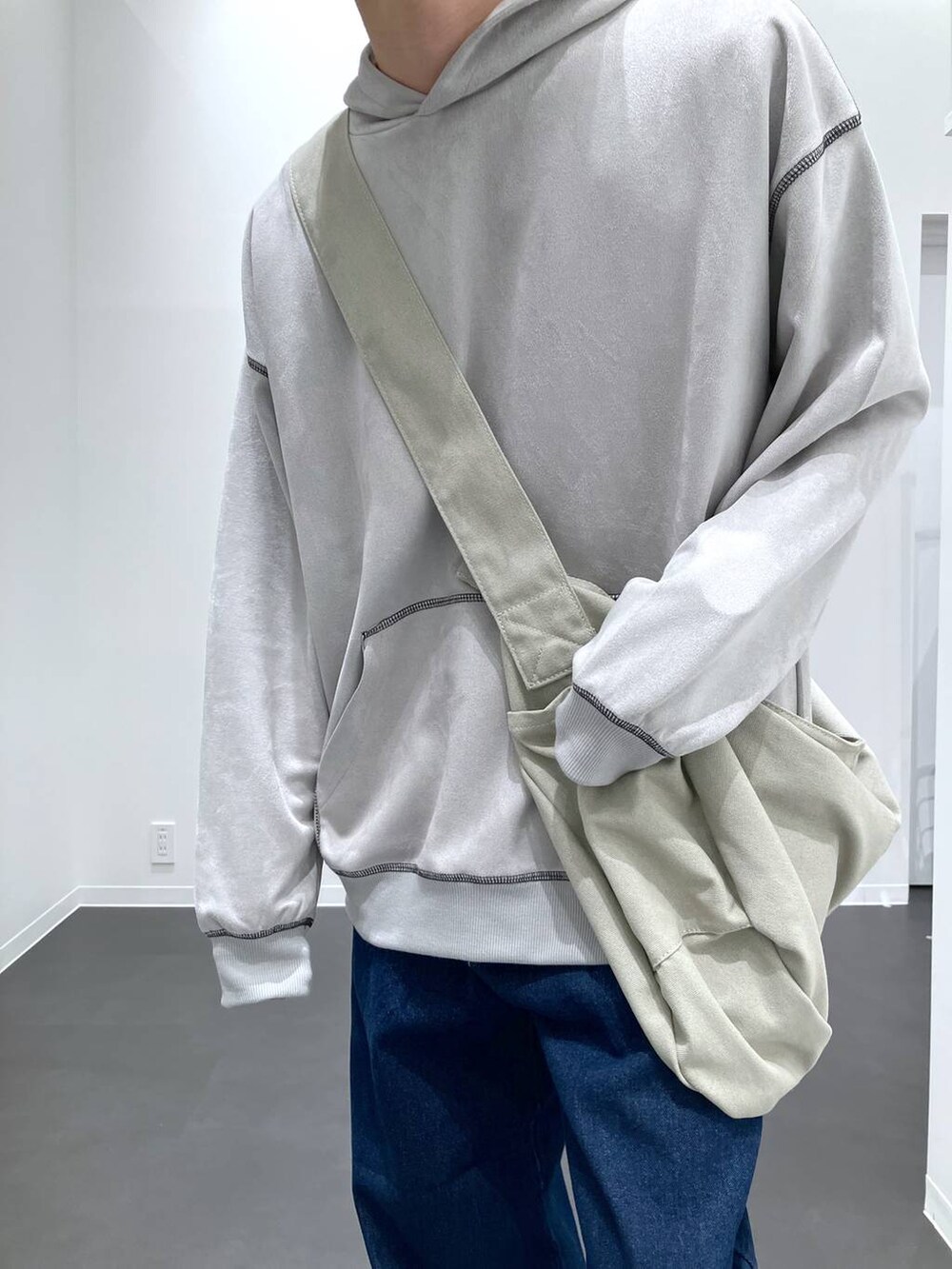 グレー系のショルダーバッグ、ブルー系のデニムパンツ、グレー系のスニーカーを着用したメンズの秋コーディネートの7枚目の写真