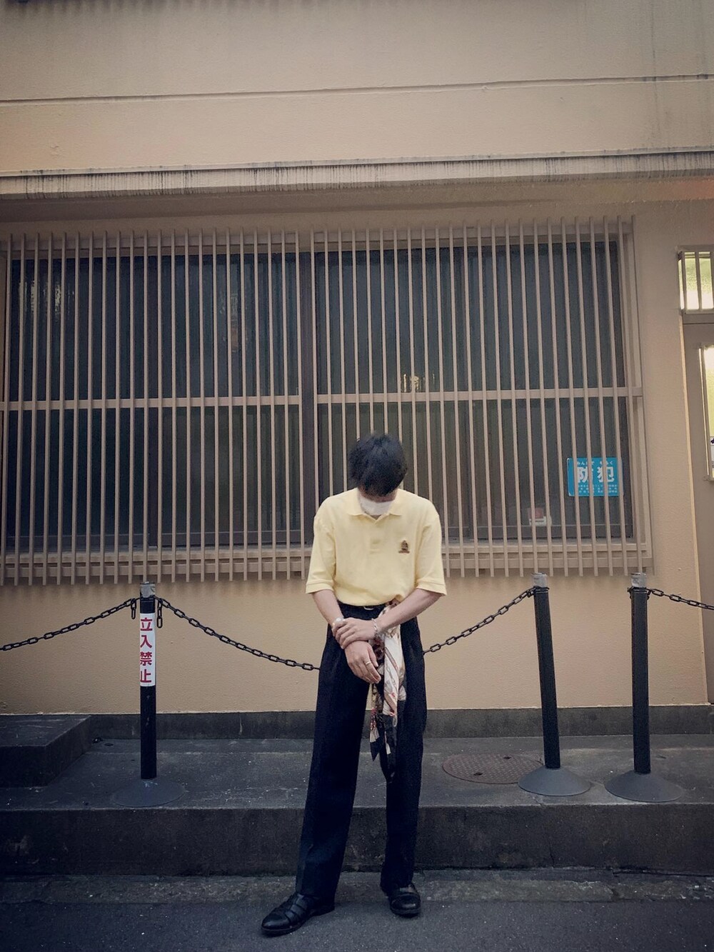 イエロー系のポロシャツ、ブラック系のサンダルを着用したメンズの春コーディネートの2枚目の写真