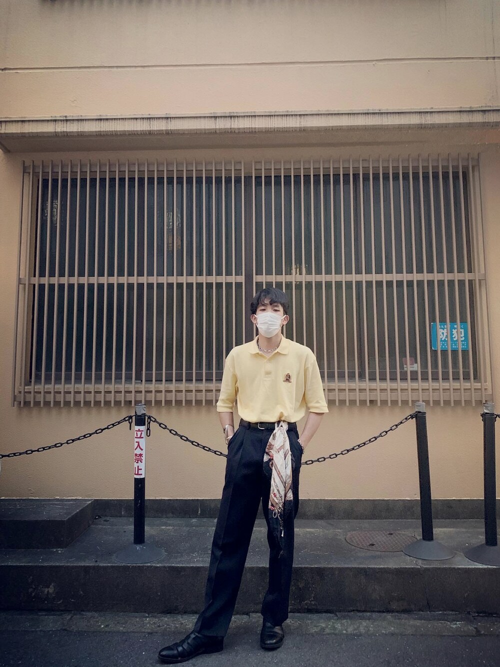 イエロー系のポロシャツ、ブラック系のサンダルを着用したメンズの春コーディネートの3枚目の写真