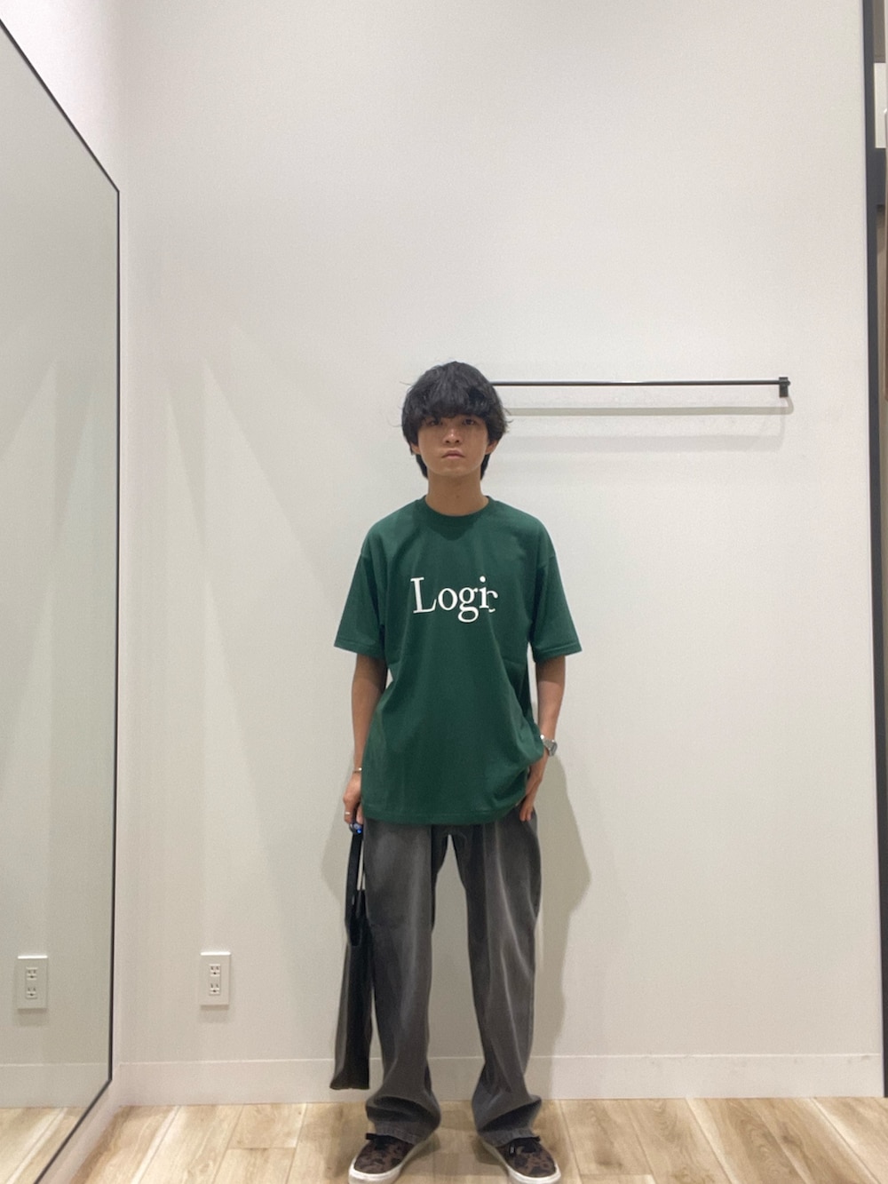 グレー系のデニムパンツ、ブラック系のトートバッグ、グリーン系のTシャツ/カットソーを着用したメンズの夏コーディネートの2枚目の写真