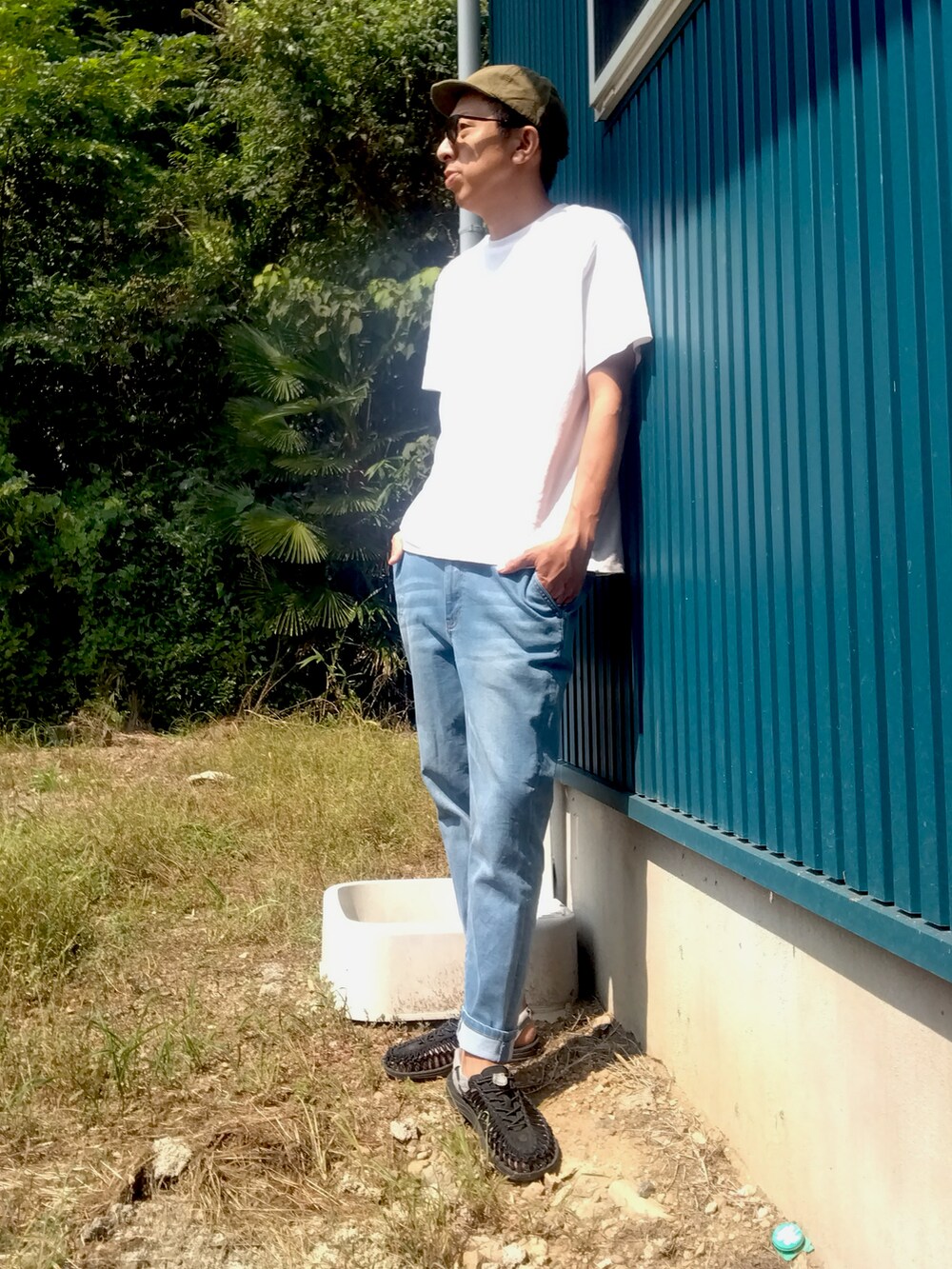 ホワイト系のTシャツ/カットソー、ブルー系のデニムパンツ、ブラック系のサンダルを着用したメンズの秋コーディネートの2枚目の写真