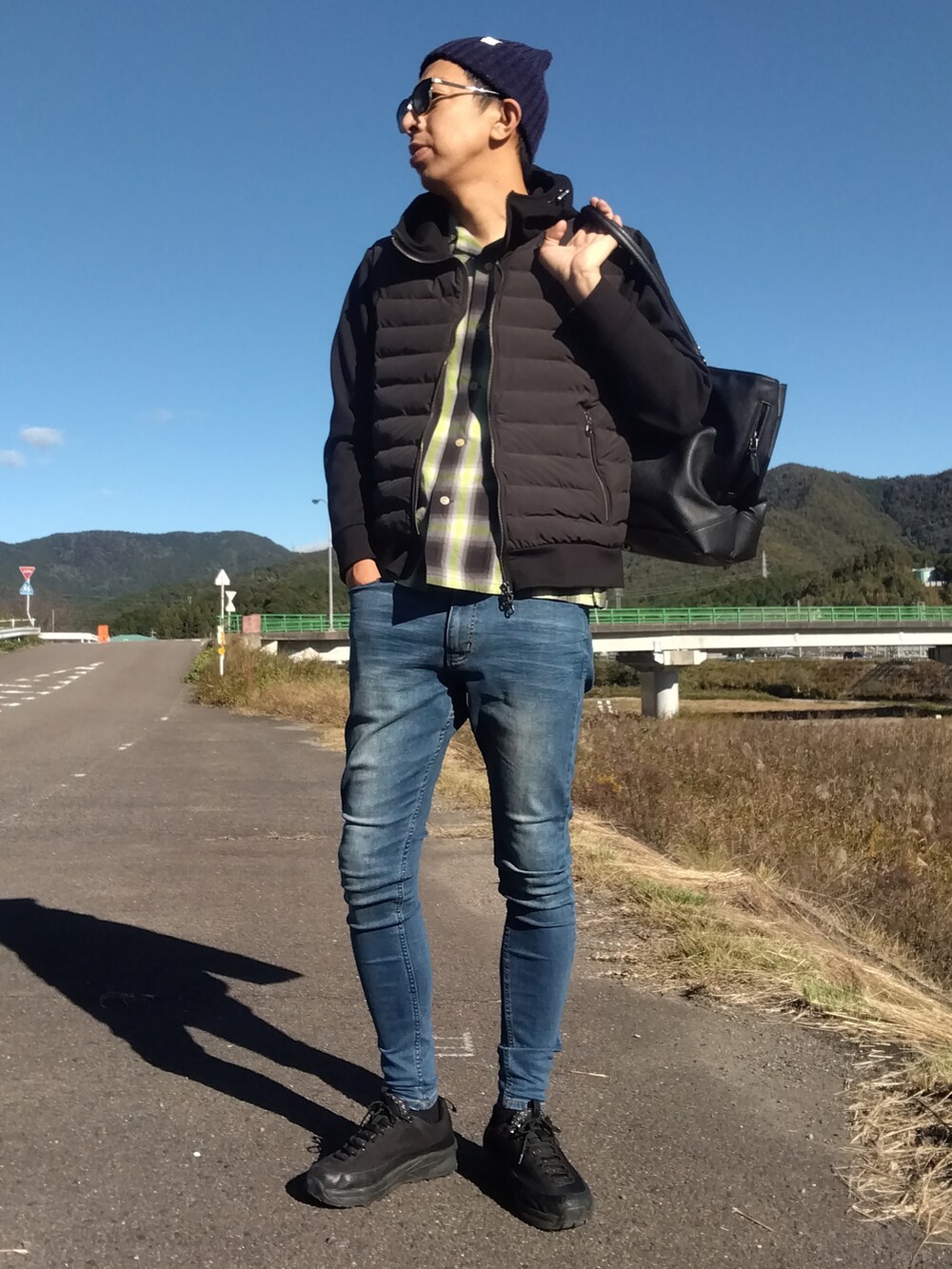 ブラック系のブルゾン、イエロー系のシャツ/ブラウス、ブルー系のデニムパンツを着用したメンズの秋コーディネートの2枚目の写真