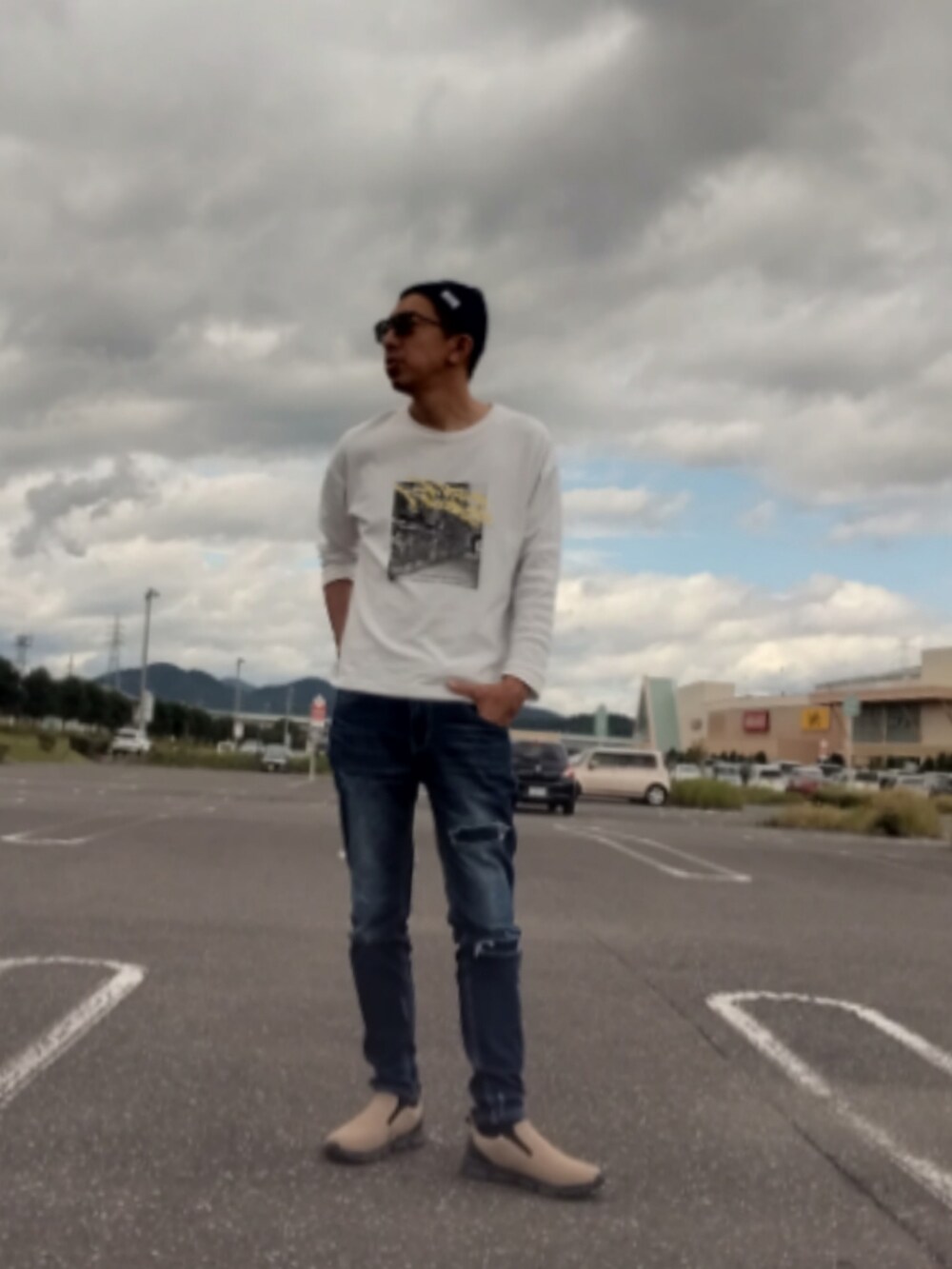 ホワイト系のTシャツ/カットソー、ブルー系のデニムパンツ、ベージュ系のスリッポンを着用したメンズの秋コーディネートの2枚目の写真