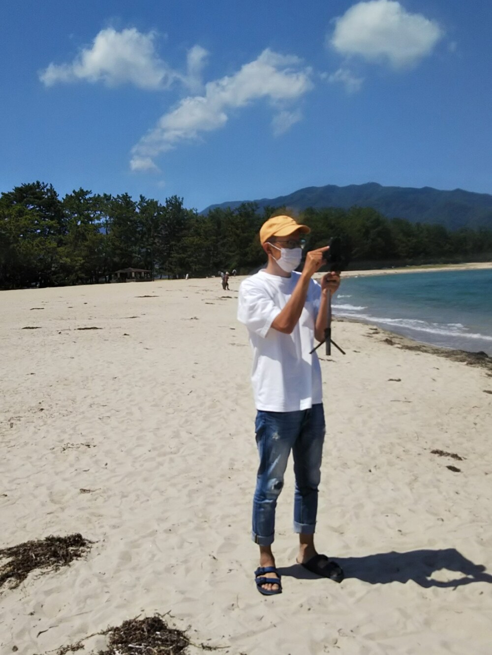 ホワイト系のTシャツ/カットソー、ブルー系のデニムパンツ、ブルー系のサンダルを着用したメンズの春コーディネートの2枚目の写真