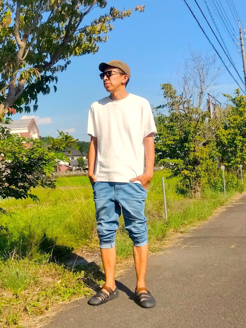 ホワイト系のTシャツ/カットソー、ブルー系のデニムパンツ、ブラック系のサンダルを着用したメンズの夏コーディネートの2枚目の写真