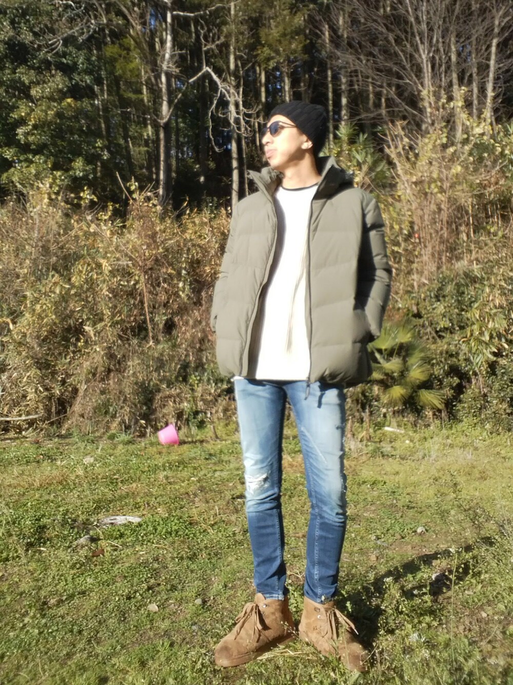 グリーン系のダウンジャケット/コート、ベージュ系のニット/セーター、ブルー系のデニムパンツを着用したメンズの冬コーディネートの2枚目の写真