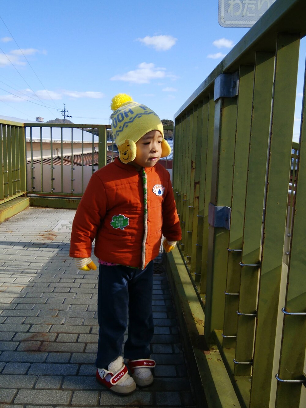 ブラック系のブルゾン、オレンジ系のニット/セーター、ブルー系のデニムパンツを着用したメンズの冬コーディネートの3枚目の写真