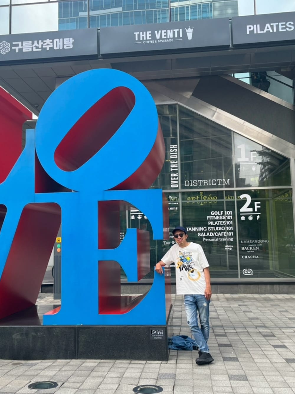 ホワイト系のTシャツ/カットソー、ブルー系のデニムパンツ、ブラック系のスニーカーを着用したメンズの春コーディネートの2枚目の写真
