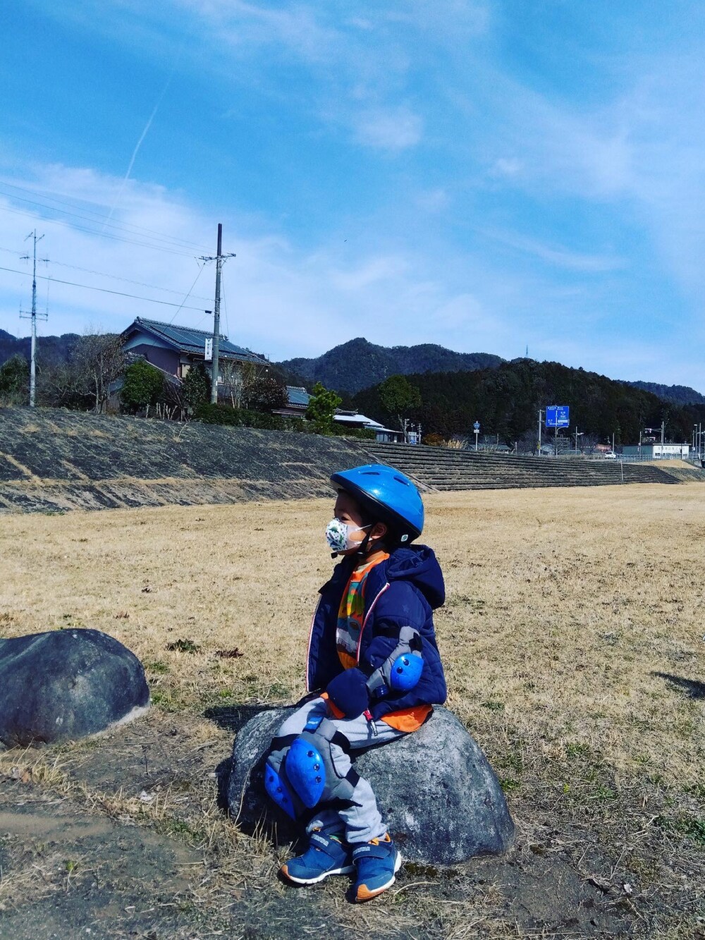 オレンジ系のニット/セーター、ブルー系のスタジャン、ブルー系のデニムパンツを着用したメンズの春コーディネートの2枚目の写真