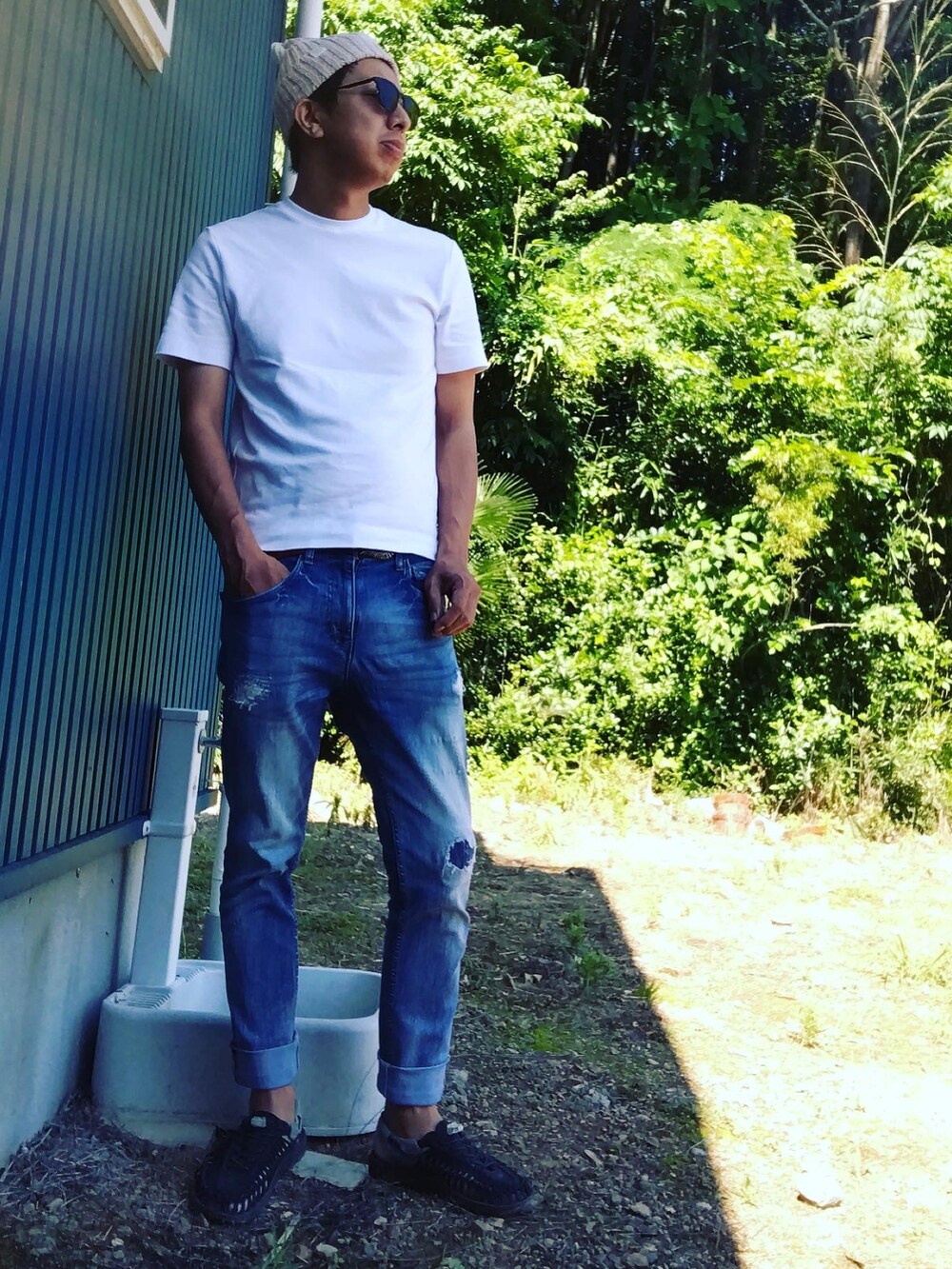 ホワイト系のTシャツ/カットソー、ブルー系のデニムパンツ、ブラック系のサンダルを着用したメンズの夏コーディネートの2枚目の写真