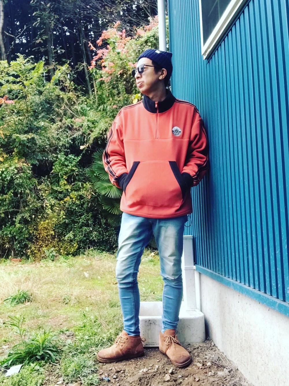 ブルー系のデニムパンツ、オレンジ系のスウェット、ブラウン系のブーツを着用したメンズの秋コーディネートの2枚目の写真