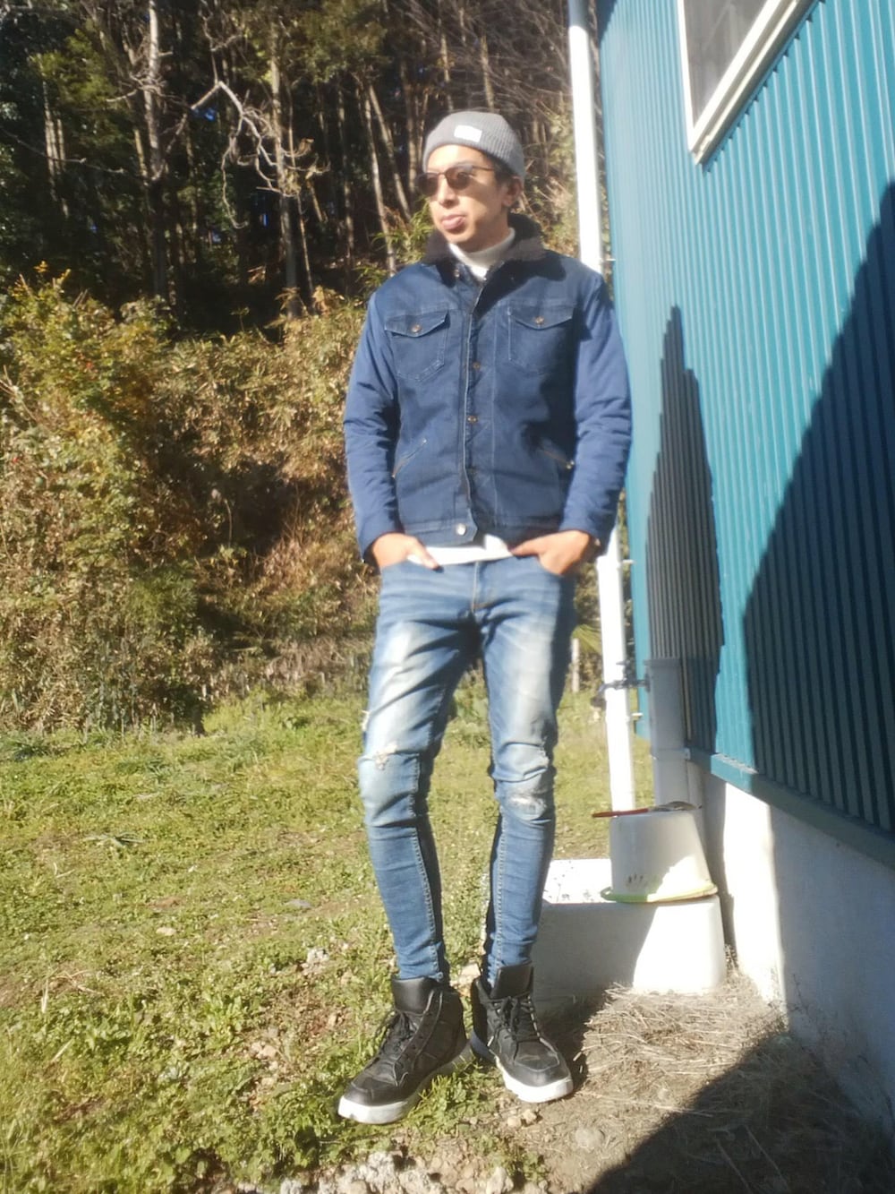 ホワイト系のニット/セーター、レッド系のシャツ/ブラウス、ブルー系のデニムパンツを着用したメンズの秋コーディネートの2枚目の写真