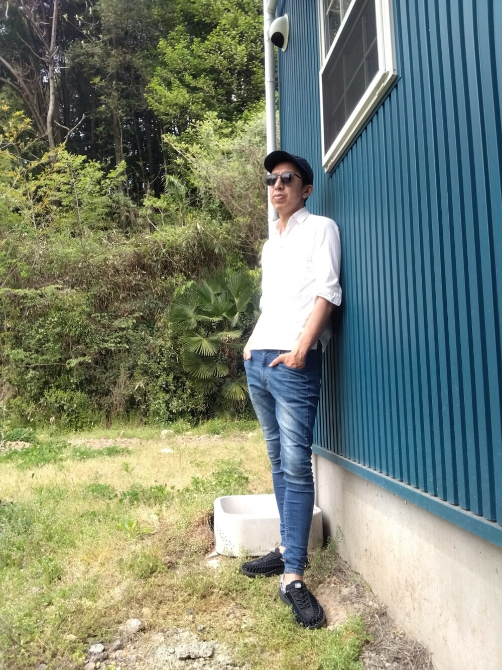 ブルー系のデニムパンツ、ホワイト系のシャツ/ブラウス、ブラック系のサンダルを着用したメンズの春コーディネートの2枚目の写真