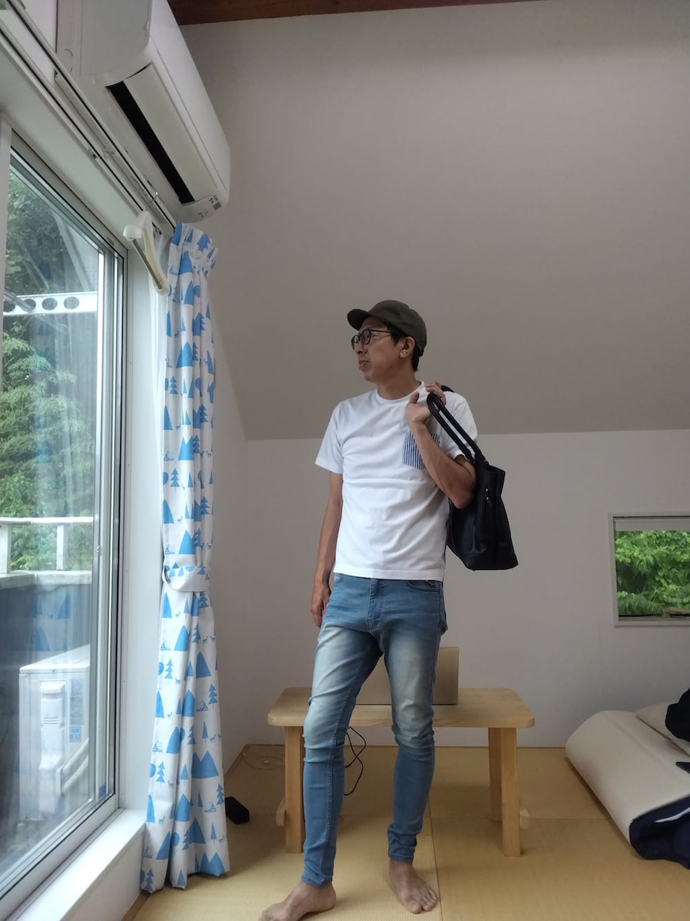 ブルー系のデニムパンツ、ブラック系のトートバッグ、ホワイト系のTシャツ/カットソーを着用したメンズの夏コーディネートの2枚目の写真