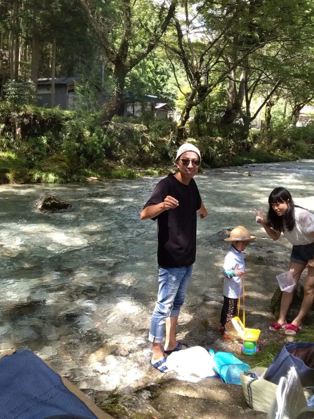 ブラック系のTシャツ/カットソー、ブルー系のデニムパンツ、ブルー系のサンダルを着用したメンズの夏コーディネートの2枚目の写真