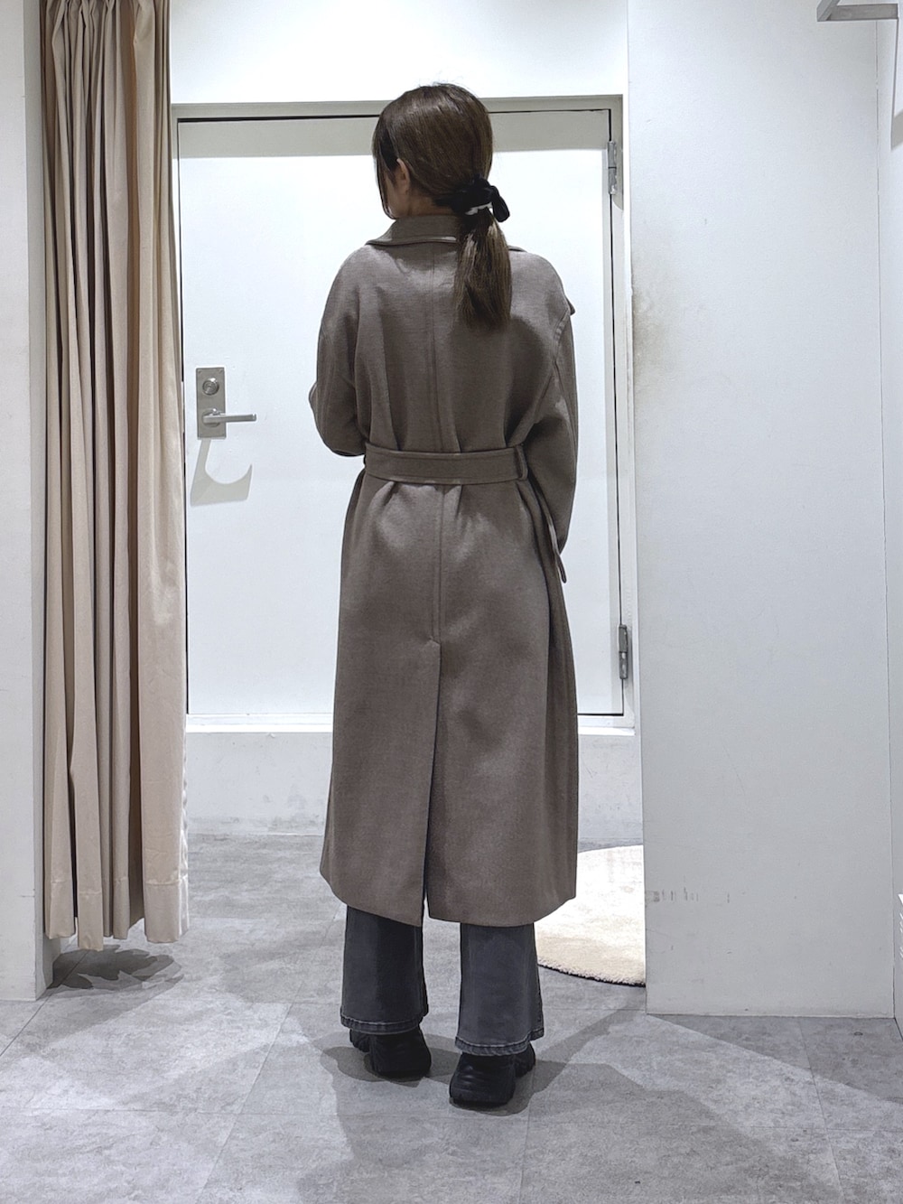 ブラウン系のステンカラーコート、ブラック系のデニムパンツ、ブラック系のショルダーバッグを着用したレディースの冬コーディネートの4枚目の写真