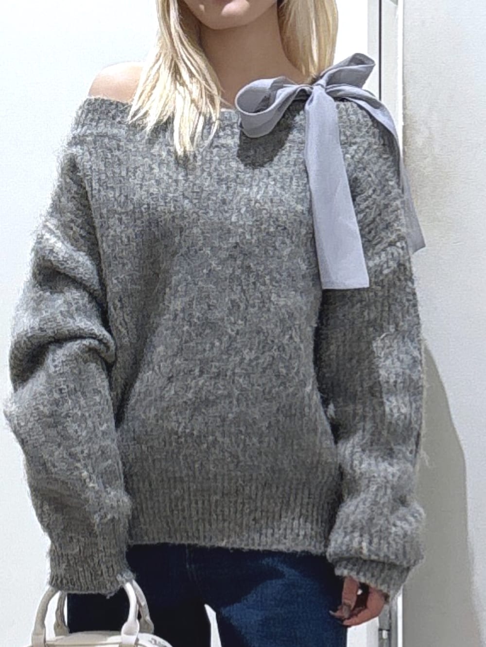 グレー系のニット/セーター、ブルー系のデニムパンツを着用したレディースの冬コーディネートの2枚目の写真