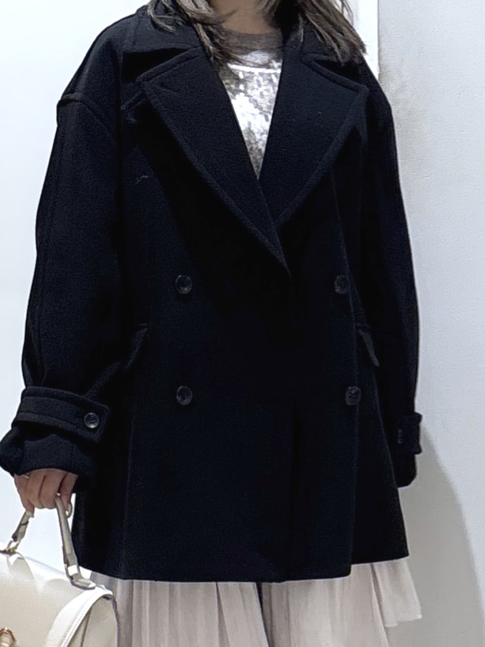 ブラック系のピーコート、ホワイト系のスカート、ブラック系のブーツを着用したレディースの冬コーディネートの2枚目の写真