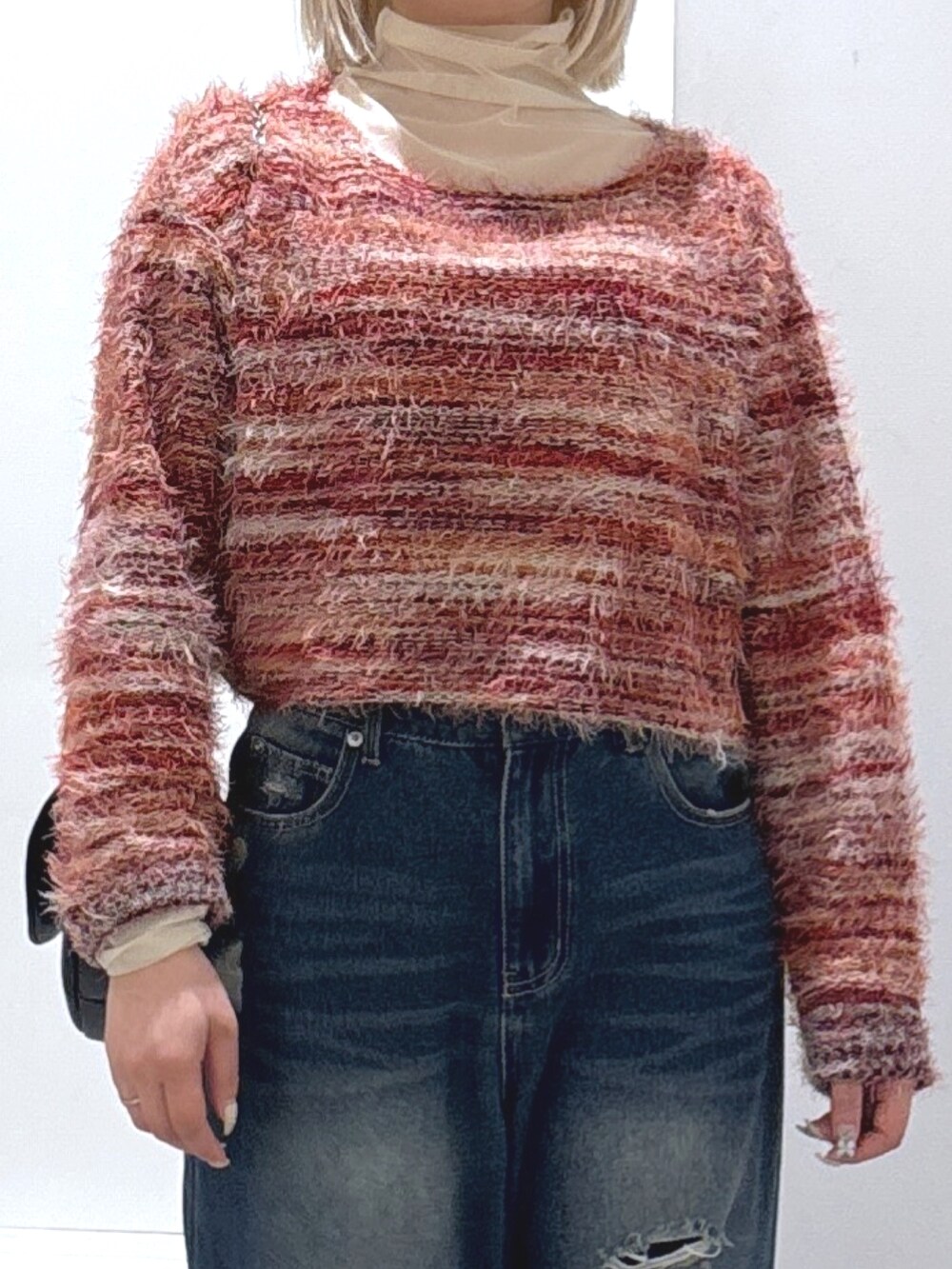 ブルー系のデニムパンツ、レッド系のニット/セーター、ホワイト系のTシャツ/カットソーを着用したレディースの冬コーディネートの2枚目の写真