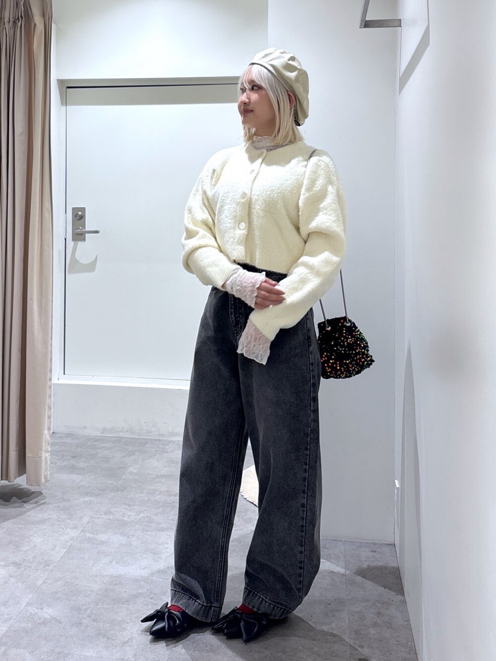 ホワイト系のニット/セーター、ブラック系のデニムパンツ、ホワイト系のTシャツ/カットソーを着用したレディースの冬コーディネートの2枚目の写真