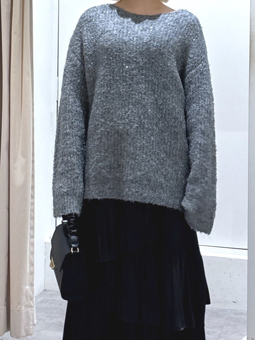 グレー系のニット/セーター、ブラック系のショルダーバッグ、ブラック系のスカートを着用したレディースの冬コーディネートの3枚目の写真