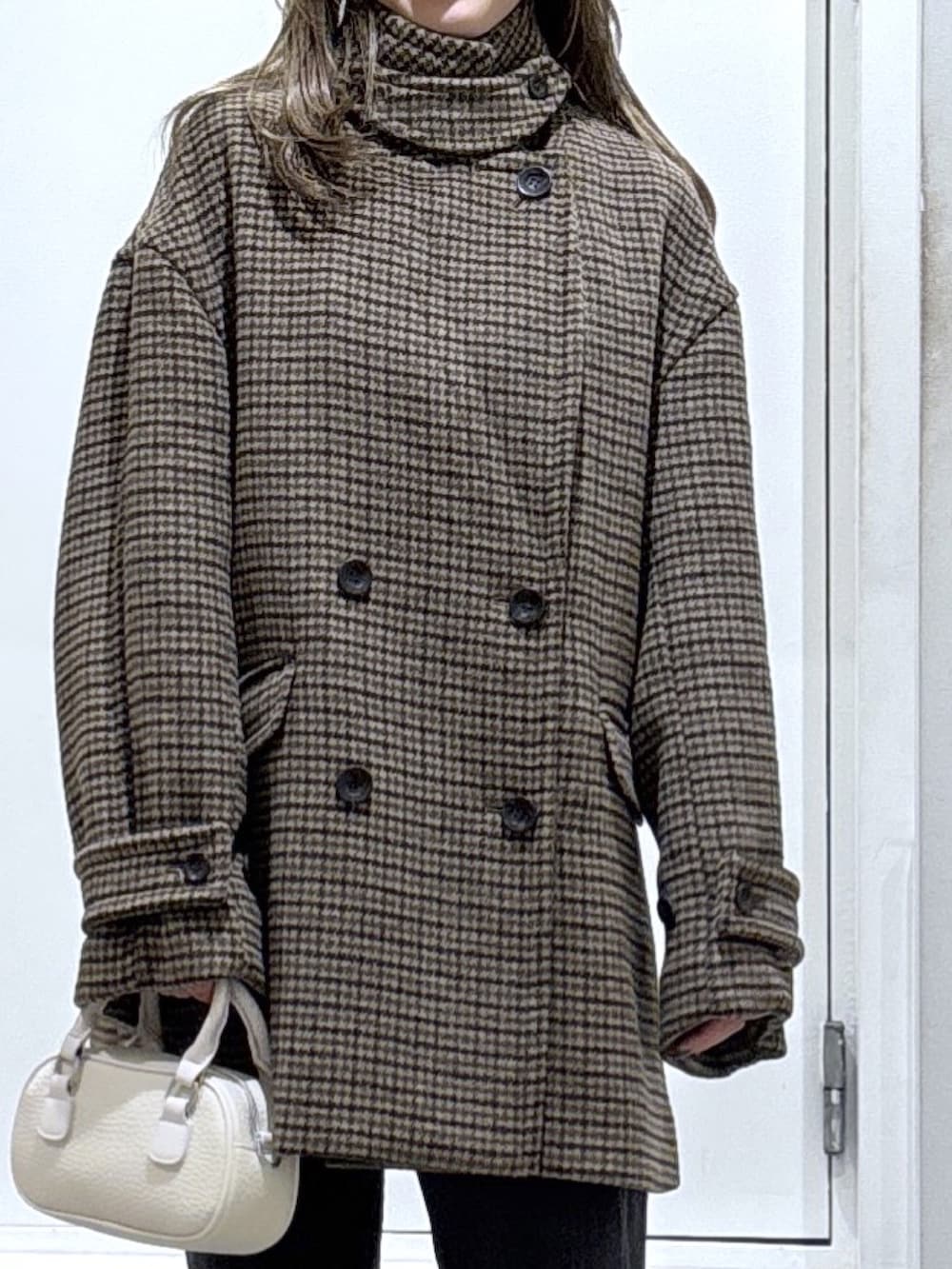 ベージュ系のピーコート、ブラック系のデニムパンツを着用したレディースの冬コーディネートの3枚目の写真