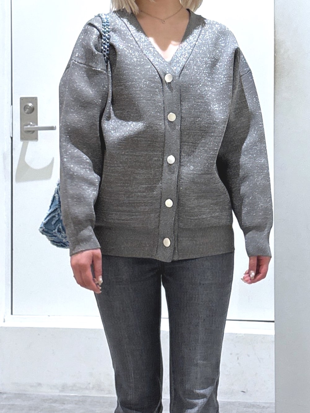 グレー系のカーディガン/ボレロ、ブラック系のデニムパンツ、ホワイト系のパンプスを着用したレディースの冬コーディネートの2枚目の写真